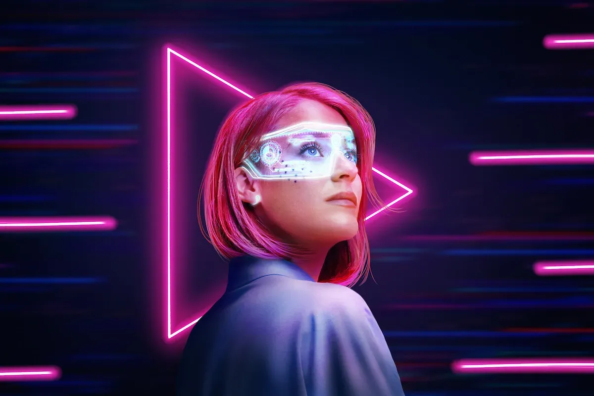 image is of a woman standing in front of a neon sign with a play button